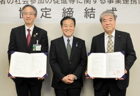 協定書を手にする（右から）ラジオ関西の桃田武司社長、パーソナリティーの三上公也さん、神戸市の森下貴浩福祉局長＝同市役所
