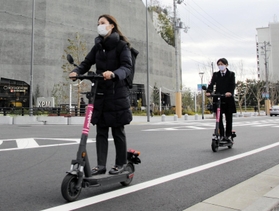 電動キックボードの実証実験で、ヘルメットをかぶらずに公道を走る神戸市職員＝神戸市中央区新港町