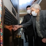 阪神・淡路大震災で妻を亡くして１９９６年に病死した父・田中秀市さんの名前が刻まれた銘板を貼り付ける、長男・田中正裕さん（手前）＝１１日午後、神戸市中央区加納町６（撮影・鈴木雅之）