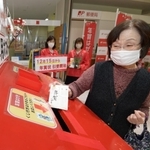 特設ポストに年賀状を投かんする女性＝１５日午前、神戸市中央区栄町通６（撮影・秋山亮太）