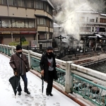 雪の積もった温泉橋を歩く観光客＝１８日午前８時５０分、新温泉町湯、湯村温泉