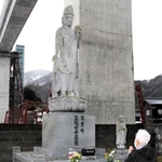 慰霊碑の観音像の前で手を合わせる北村忠久さん＝２８日午後、兵庫県香美町香住区余部