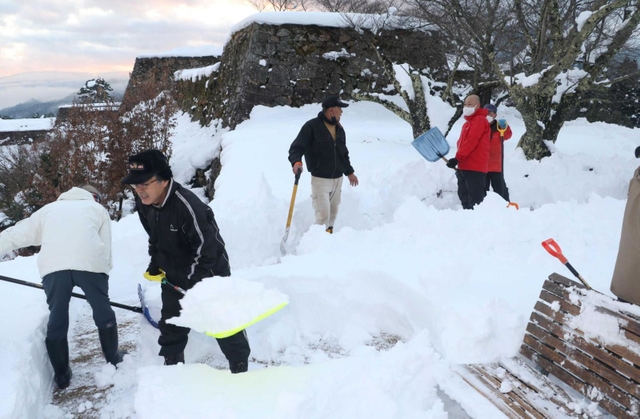 朝来市職員やボランティアガイドら約２５人が参加して雪かきをした＝２０２１年１２月２８日夕、竹田城跡