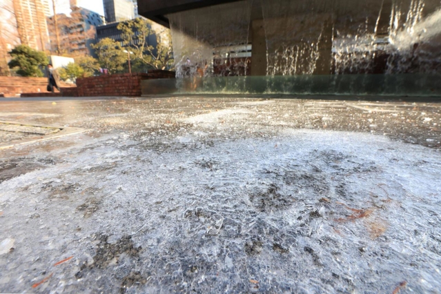 厳しい冷え込みで凍結した水たまり＝１４日午前、神戸市中央区加納町６、東遊園地