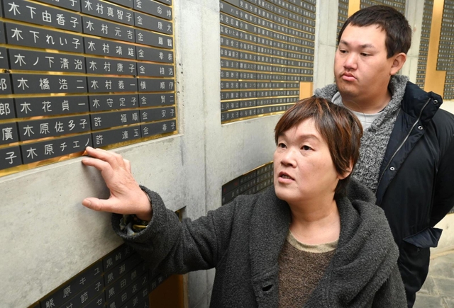 阪神・淡路大震災で亡くなった木原チエノさんの銘板に触れ、思いを語る末広真由美さん（手前）と大樹さん＝神戸市中央区加納町６