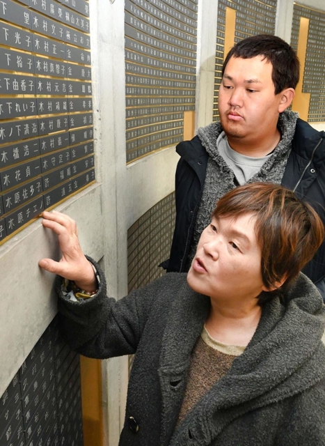 阪神・淡路大震災で亡くなった木原チエノさんの銘板に触れ、思いを語る末広真由美さん（手前）と大樹さん＝神戸市中央区加納町６