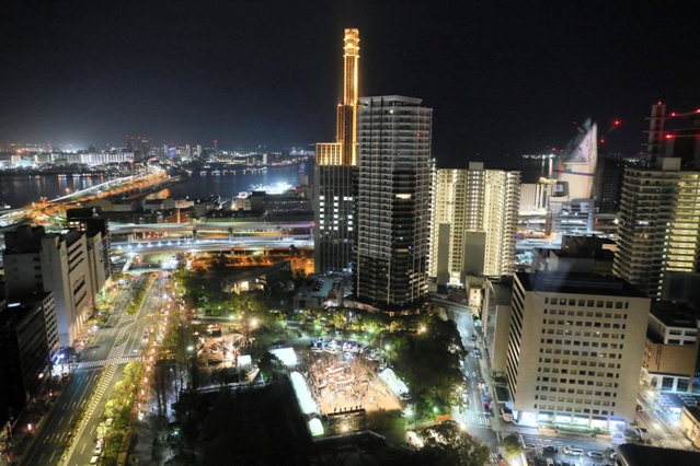 夜が明けきらない神戸。街明かりや灯籠の灯（中央）が輝く＝１７日早朝、神戸・三宮、東遊園地