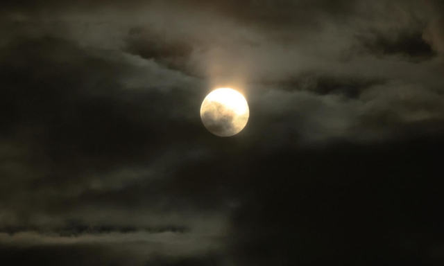 ２０２２年で地球から最も遠く小さく見える満月「ミニマムムーン」。薄雲をまとい、怪しい雰囲気を放つ＝１８日午後６時３１分、神戸市中央区東川崎町１、神戸新聞社から（撮影・鈴木雅之）