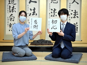 新年の抱負を書いた色紙を手に笑顔の藤井聡太王位（右）と里見香奈女流王位＝関西将棋会館