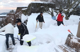 朝来市職員やボランティアガイドら約２５人が参加して雪かきをした＝２０２１年１２月２８日夕、竹田城跡