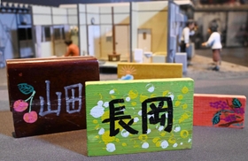 カラフルな手作り表札。背景は仮設住宅の生活を伝えるジオラマ