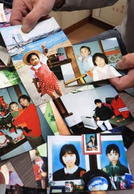 家族の写真を手に話す羽中健二さん。帽子をかぶり愛らしい表情を見せる愛梨ちゃんや、幼い敬登さんを抱き、笑顔を見せる妻の幸恵さんが写る＝神戸市内