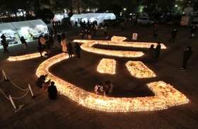 「１・１７のつどい」の会場に浮かび上がった「忘」の文字＝１６日午後６時２９分、神戸市中央区加納町６（撮影・小林良多）