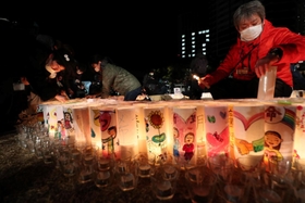紙灯籠に火をともす人たち＝１７日午前４時４９分、神戸市中央区加納町６、東遊園地（撮影・辰巳直之）