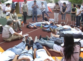 ２００８年の中国・四川大地震で被災地を訪れた冨永良喜教授（左）。リラックス法を伝えた（提供写真）