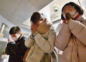 子どもたちと「慰霊と復興のモニュメント」にある地下の「瞑想空間」を訪れ、銘板に手をあわす吉田綾香さん（中央）＝１７日午前５時３８分、神戸市中央区加納町６、東遊園地（撮影・秋山亮太）