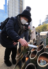 竹灯籠に火をともす高橋一子さん＝１７日午後０時５９分、神戸市中央区加納町６、東遊園地（撮影・鈴木雅之）