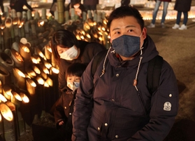 亡くなった祖父の慰霊のため東遊園地を訪れた大前敏郎さん（右）。竹灯ろうに明かりをともしながら長男に祖父のことを話して聞かせた＝１７日午後、神戸市中央区加納町６（撮影・小林良多）