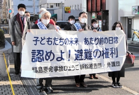本人尋問を前に、神戸地裁前で横断幕を掲げる原告団＝２０日午前、神戸市中央区橘通２