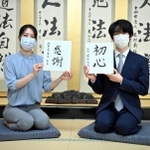 新年の抱負を書いた色紙を手に笑顔の藤井聡太王位（右）と里見香奈女流王位＝関西将棋会館