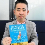 著書「おばあちゃんは、ぼくが介護します。」を手にする奥村シンゴさん。祖母が色を付けた塗り絵を前に「介護を強いられる若者の環境を改善したい」と語る＝神戸市内