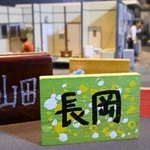 カラフルな手作り表札。背景は仮設住宅の生活を伝えるジオラマ