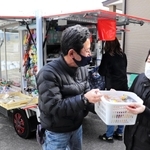 なじみになった客から買い物かごを受け取る「とくし丸」販売員の野崎敏郎さん＝淡路市江井