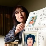 母正子さんのちらしを手にする佐藤悦子さん。手前は母の写真と焼け跡から見つかった腕時計や小銭＝加古川市内（撮影・中西幸大）