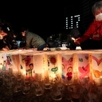 紙灯籠に火をともす人たち＝１７日午前４時４９分、神戸市中央区加納町６、東遊園地（撮影・辰巳直之）