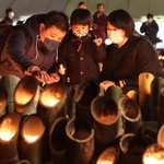 亡くなった祖父の慰霊のため東遊園地を訪れた大前敏郎さん（左）。竹灯ろうに明かりをともしながら長男に祖父のことを話して聞かせた＝１７日午後、神戸市中央区加納町６（撮影・小林良多）