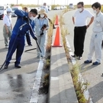 除草方法のアイデアコンテストで、道路脇の雑草に熱湯をかけていく参加者＝昨年１０月、尼崎市内（県西宮土木事務所提供）