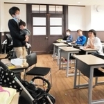 長女を抱きながら「働き方」の授業をする灘高校の片田孫朝日教諭（左）＝神戸市東灘区魚崎北町８（本人提供）