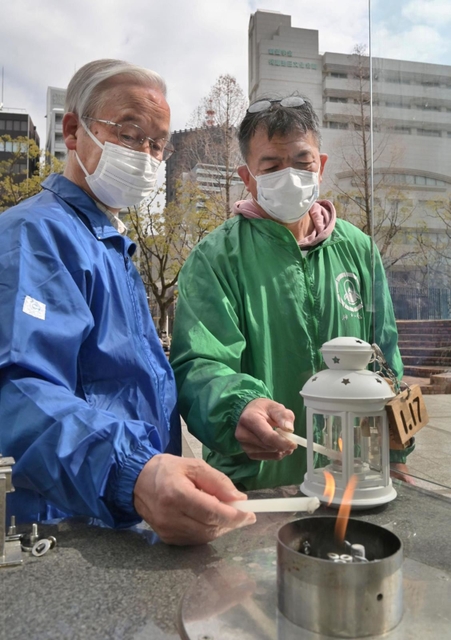 「１・１７希望の灯り」の火をランタンに移す杉山正秀代表（右）と高橋守雄所長＝神戸市中央区加納町６（撮影・秋山亮太）