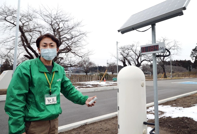 ＪＲ夜ノ森駅前で線量計を手にするガイドの里見喜生さん＝福島県富岡町