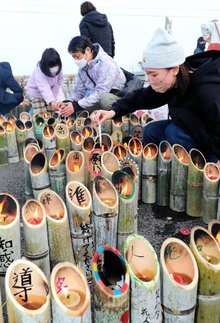 兵庫から運んだ竹灯籠に火をともす参加者＝１１日午後２時３６分、宮城県名取市閖上東