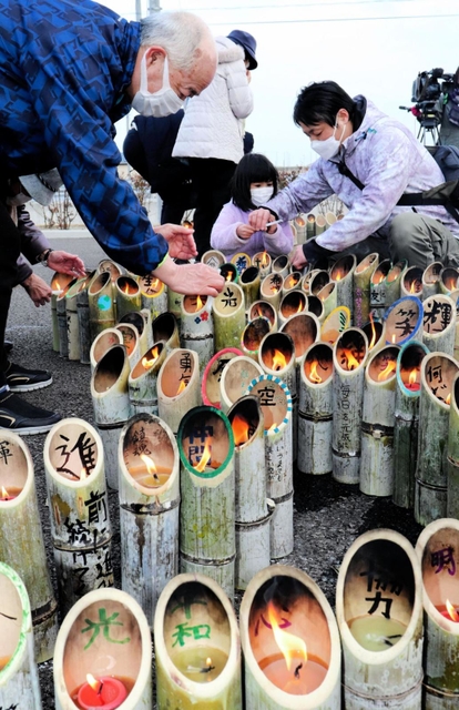 兵庫から運んだ竹灯籠に火をともす参加者＝１１日午後２時３５分、宮城県名取市閖上東