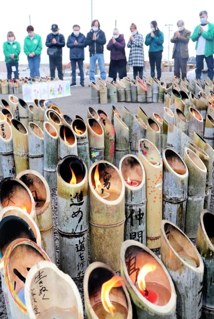 竹灯籠を囲み、黙とうをささげる兵庫のボランティアや近隣住民ら＝１１日午後、宮城県名取市閖上東