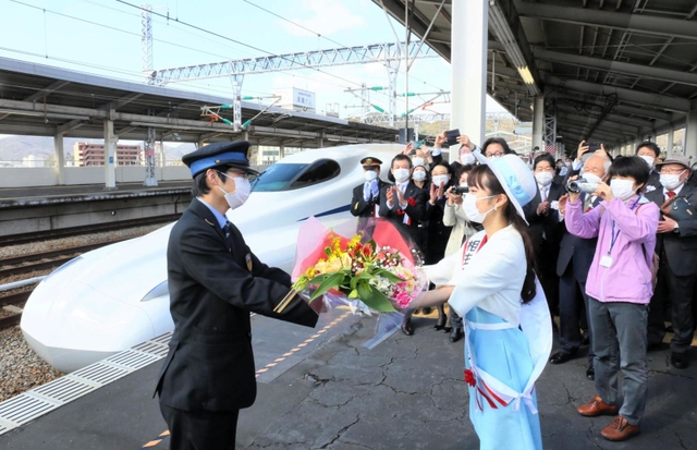 相生みなとの女王（右）から花束を贈られる新幹線運転士＝１５日午前９時４５分、兵庫県相生市の相生駅（撮影・大山伸一郎）
