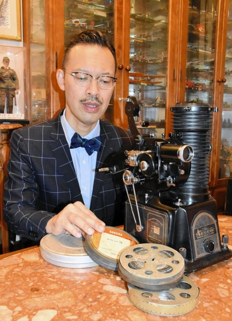 岡部芳郎さんの数少ない遺品である映写機とフィルムを手に、足跡を語る孫の芳彦さん＝神戸市灘区