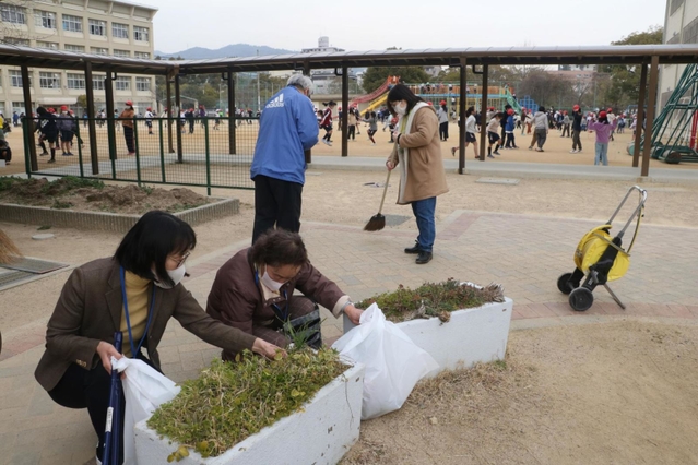 フェンスがなかった今月９日、昼休みに校庭を走り回る児童の近くで、公園を清掃していた地域住民ら。神戸市内で唯一の光景だった＝神戸市灘区備後町１、成徳小学校