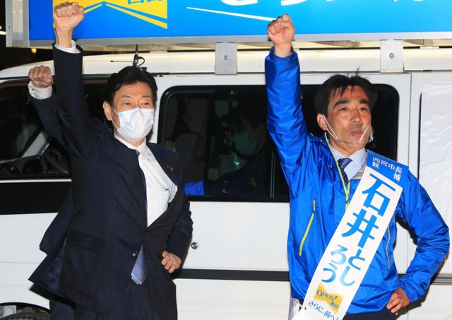 石井登志郎氏（右）の勝利に向けて拳を突き上げる、自民党兵庫県連会長の西村康稔衆院議員＝２５日午後、西宮市高松町（撮影・斎藤雅志）