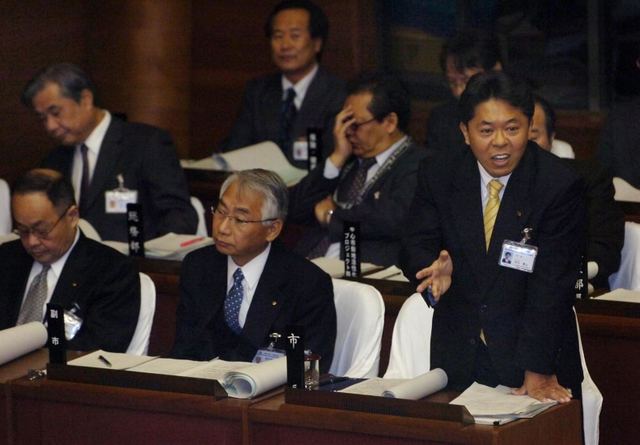 市議会で厳しい質問に対し答弁する北口寛人市長（右）＝２０１０年１２月７日、明石市役所