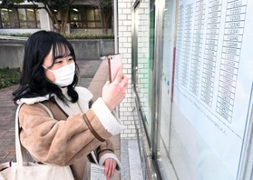 合格を確認し、張り出された番号を写真撮影する受験生＝７日午前、神戸市西区学園東町９、神戸市外国語大学（撮影・坂井萌香）