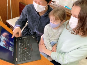 ウクライナの故郷を訪れたときの写真を娘と一緒に見る川瀬イダさん（右）と夫の弓弦さん＝神戸市垂水区大町３