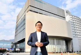 兵庫県立大大学院減災復興政策研究科が入る「人と防災未来センター」の前で２拠点生活の可能性を語る佐藤敬生さん＝神戸市中央区脇浜海岸通１