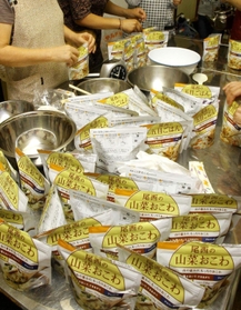 一斉避難訓練で非常食のアルファ化米で炊き出しの用意をする女性ら＝養父市内（資料写真）