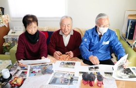 仮設住宅の写真などを前に再会を喜ぶ高橋守雄所長（右）と佐藤清太郎さん、妻京子さん＝宮城県南三陸町志津川