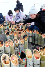 兵庫から運んだ竹灯籠に火をともす参加者＝１１日午後２時３６分、宮城県名取市閖上東
