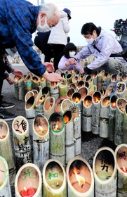 兵庫から運んだ竹灯籠に火をともす参加者＝１１日午後２時３５分、宮城県名取市閖上東