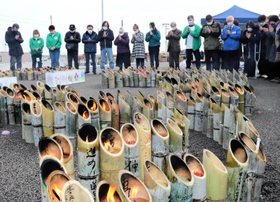 竹灯籠を囲み、黙とうをささげる兵庫のボランティアや近隣住民ら＝１１日午後、宮城県名取市閖上東